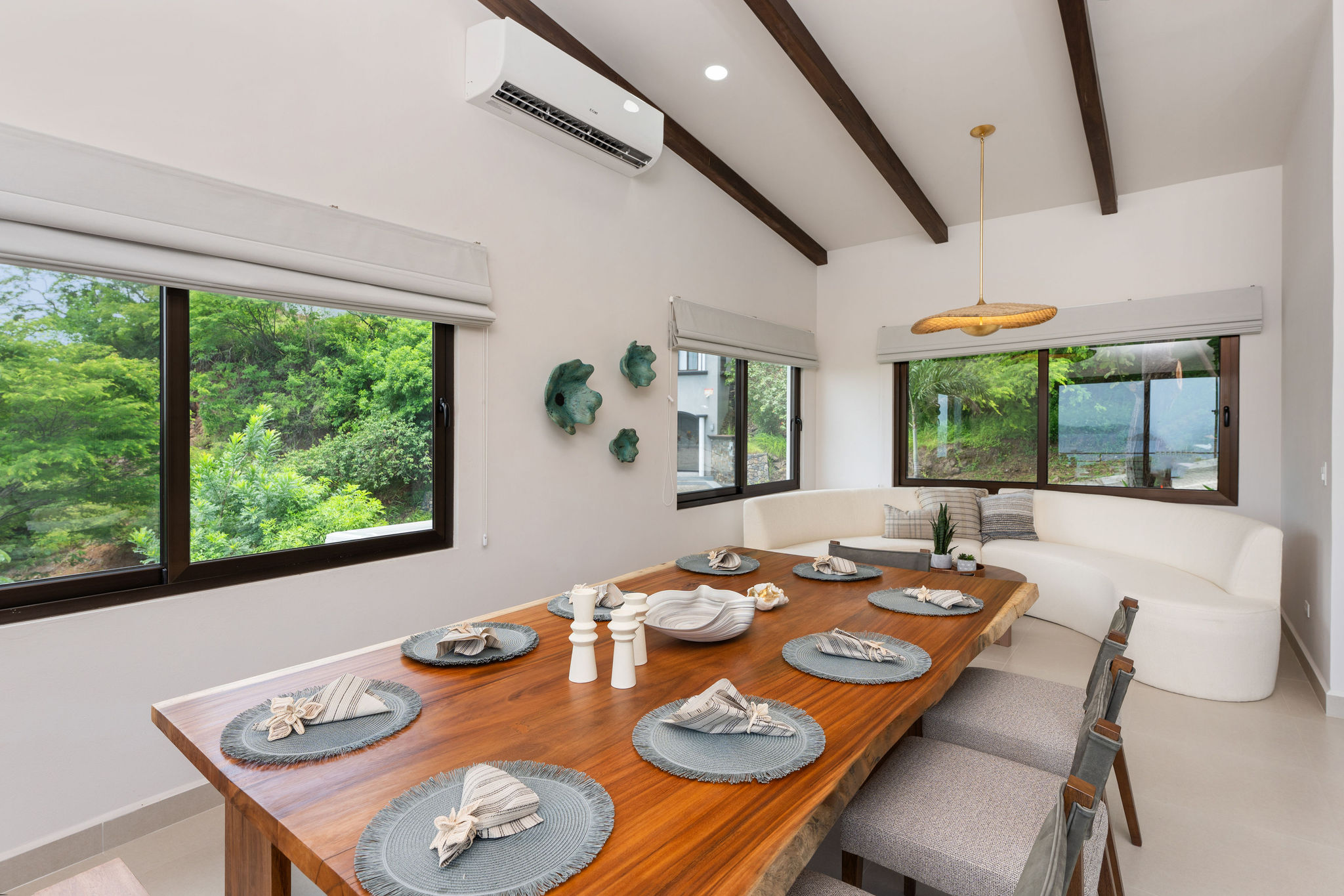 Dining area set for a group, with tropical greenery outside
