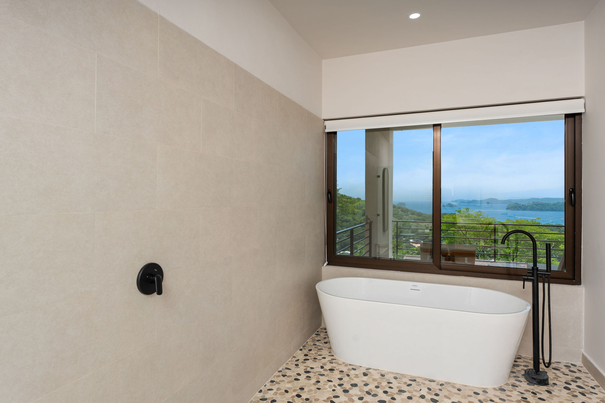 Freestanding bathtub beside a window overlooking the bay